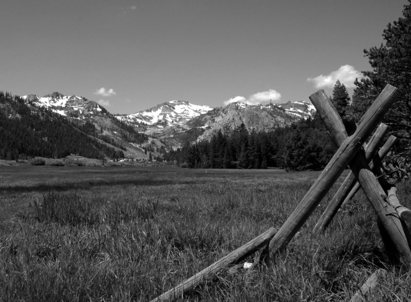 Black and white image of the meadow and mountains of Olympic Valley. Snow on peaks.